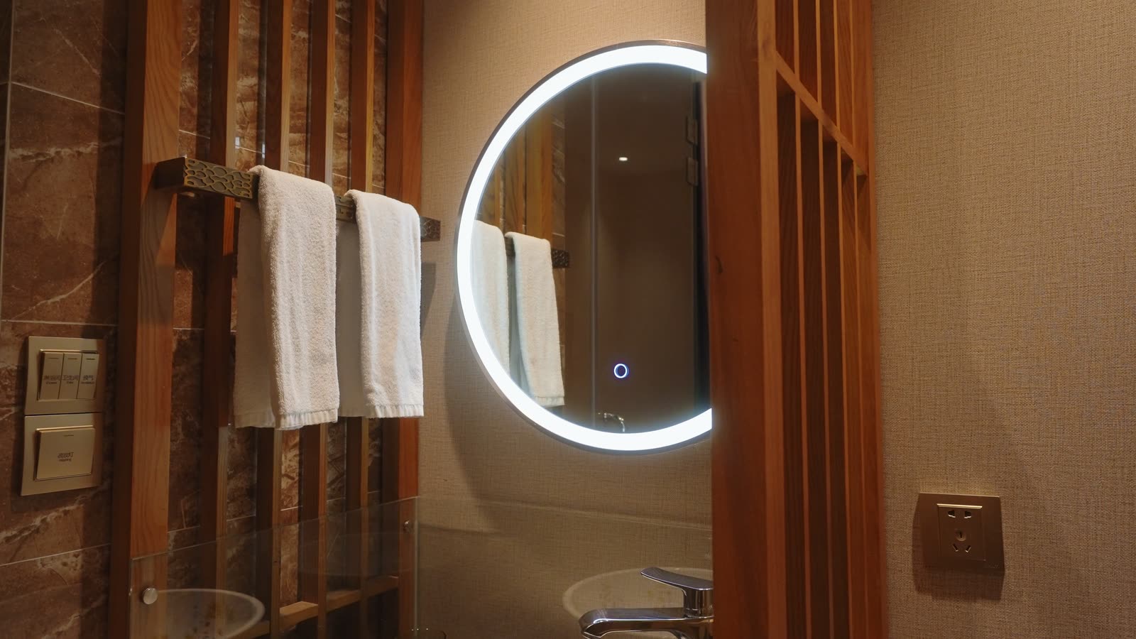 Bir otel banyosunda aydınlatmalı ayna ve katlı havlular